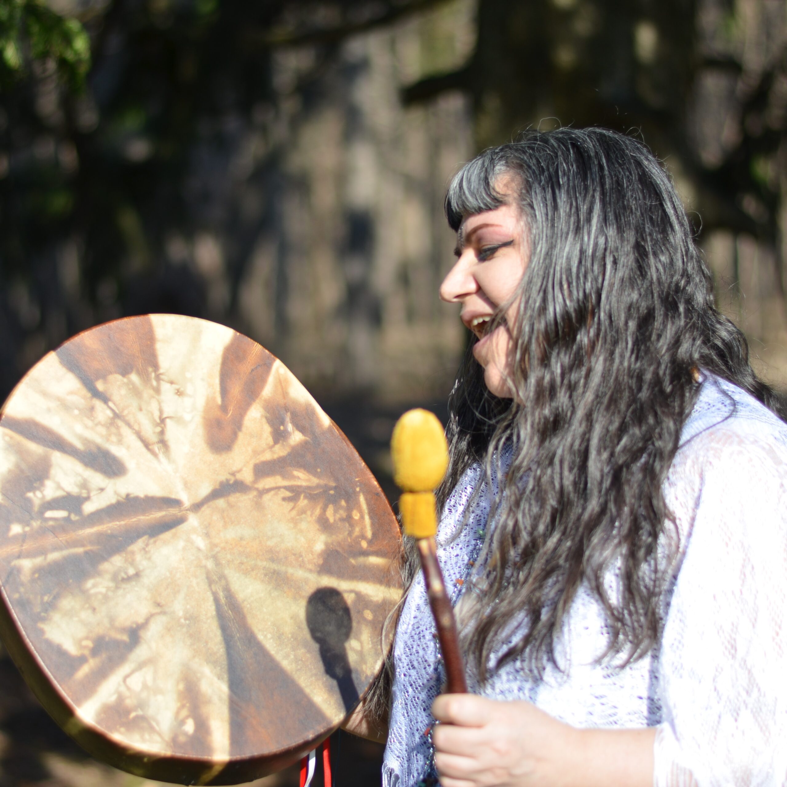 Indigenous Singer Brenda MacIntyre, Medicine Song Woman, singing and hand drumming outside, side view