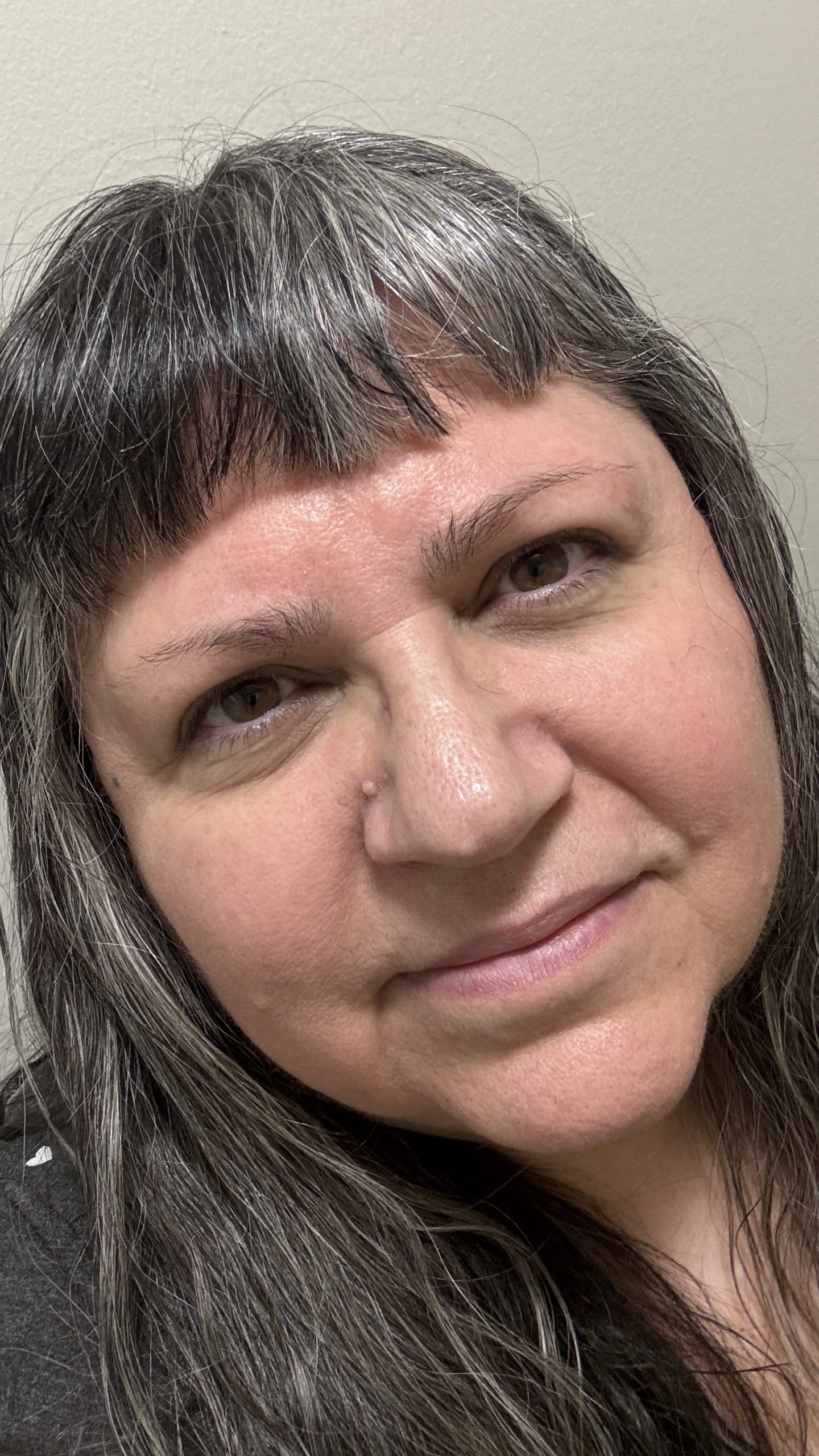 Brenda MacIntyre, Medicine Song Woman Casual head shot of light-skinned Indigenous woman. She has long dark and silver hair with bangs and a slight smile.